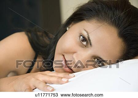 Stock Image - Portrait of Hispanic young adult woman lying down.. Fotosearch