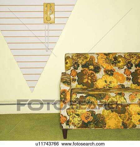 Stock Photograph - Retro floral printed sofa with yellow rotary phone hanging on wall.. Fotosearch