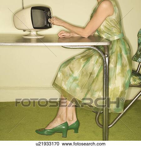 Side view of Caucasian mid-adult woman wearing green vintage dress sitting at 50's retro dinette set turning old televsion knob. View Large Photo Image Stock Image - Side view of Caucasian mid-adult woman wearing green vintage dress sitting at 50's retro dinette set turning old televsion knob.. Fotosearch