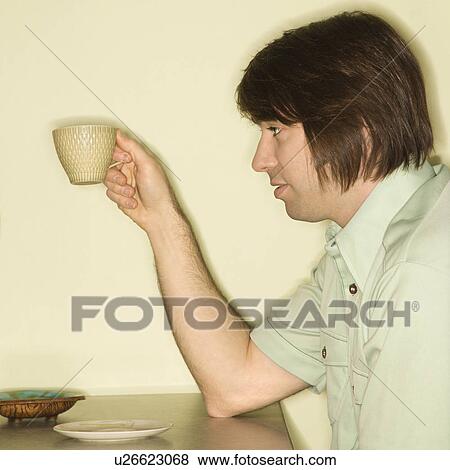 Side view of mid-adult man holding up coffee cup View Large Photo Image Stock Photo - Side view of mid-adult man holding up coffee cup. Fotosearch