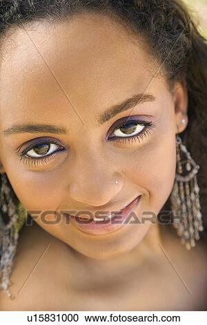 Stock Image - Close-up of young-adult Black woman making eye contact.. Fotosearch
