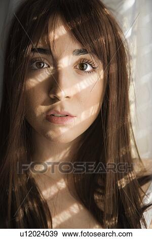 Stock Photo - Portrait of pretty Caucasian young woman with sunlight through window.. Fotosearch