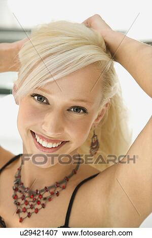 Stock Photo - Woman holding up hair smiling. Fotosearch