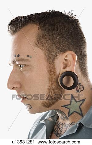 Stock Image - Caucasian mid-adult man with tattoos and piercings.. Fotosearch