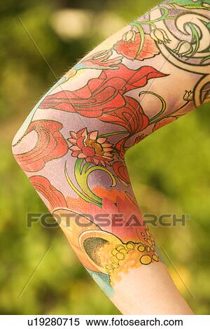 Stock Photography - Close up of floral tattoo on arm of Caucasian woman.. Fotosearch