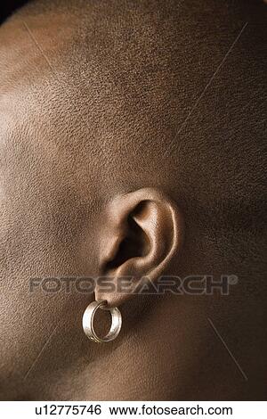 Stock Photograph - Side view portrait of African-American mid-adult man wearing earring.. Fotosearch