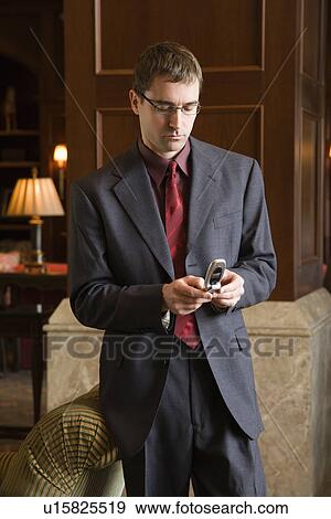 Businessman looking down and his cellphone View Large Photo Image Stock Photo - Businessman looking down and his cellphone. Fotosearch