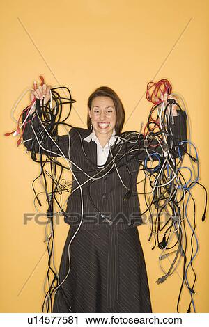 Stock Image - Happy business woman holding tangled cords. Fotosearch