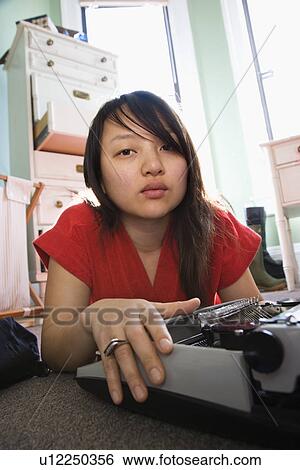 Pretty Asian young woman lying on floor in red robe typing on typewriter. View Large Photo Image Stock Photograph - Pretty Asian young woman lying on floor in red robe typing on typewriter.. Fotosearch
