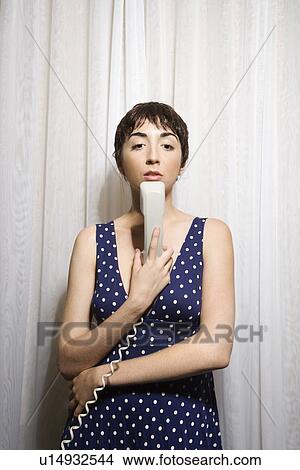 Pretty Caucasian young woman holding telephone receiver to chin. View Large Photo Image Picture - Pretty Caucasian young woman holding telephone receiver to chin.. Fotosearch