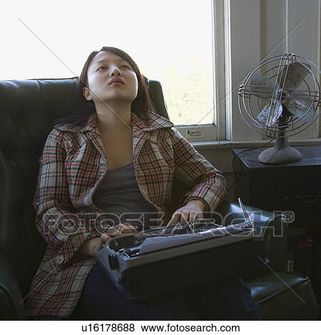 Young woman with a typewriter on her lap sitting in an armchair View Large Photo Image Stock Photo - Young woman with a typewriter on her lap sitting in an armchair. Fotosearch