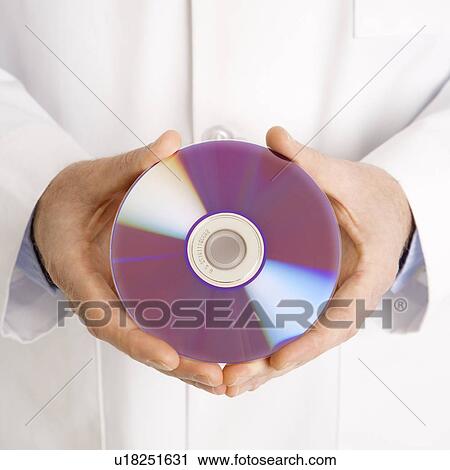 Stock Image - Close up of Caucasian mid adult male physician holding compact disc.. Fotosearch
