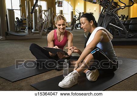 Stock Photo - Adult female with personal trainer at gym. Fotosearch