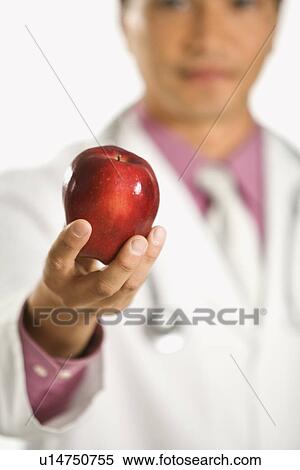 Stock Photography - Asian American male doctor holding out apple.. Fotosearch