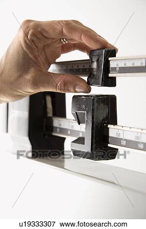 Stock Photo - Female's hand on scale to figure out her weight. Fotosearch