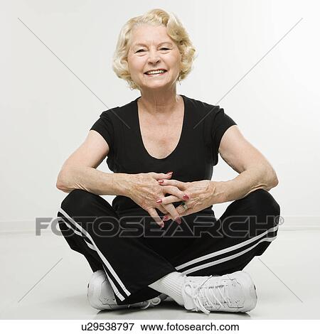 Stock Photo - Woman sitting on floor with legs crossed. Fotosearch