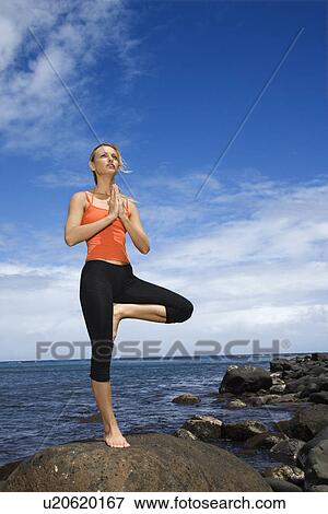 Young adult woman doing yoga on rocky shore View Large Photo Image Stock Photo - Young adult woman doing yoga on rocky shore. Fotosearch