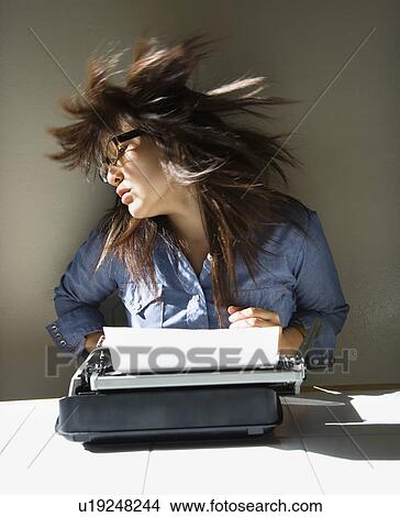 Pretty young Asian woman sitting at typewriter swinging head and hair around. View Large Photo Image Picture - Pretty young Asian woman sitting at typewriter swinging head and hair around.. Fotosearch