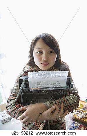 Stock Image - Pretty young woman holding typewriter. Fotosearch