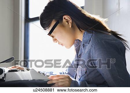 Pretty young woman sitting in chair typing on typewriter in kitchen View Large Photo Image Stock Image - Pretty young woman sitting in chair typing on typewriter in kitchen. Fotosearch