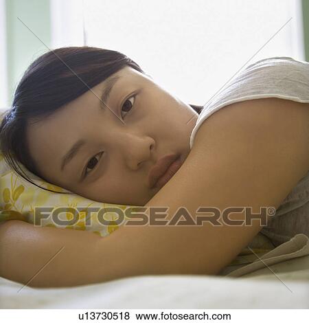 Stock Photo - Woman lying in bed with head on pillow. Fotosearch