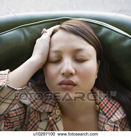 Stock Image - Woman sitting in green chair with eyes closed. Fotosearch