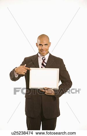 Picture - Holding and pointing to blank sign standing against white background. Fotosearch