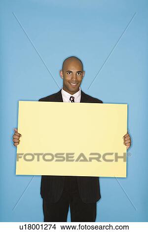 Man holding blank sign against blue background View Large Photo Image Picture - Man holding blank sign against blue background. Fotosearch