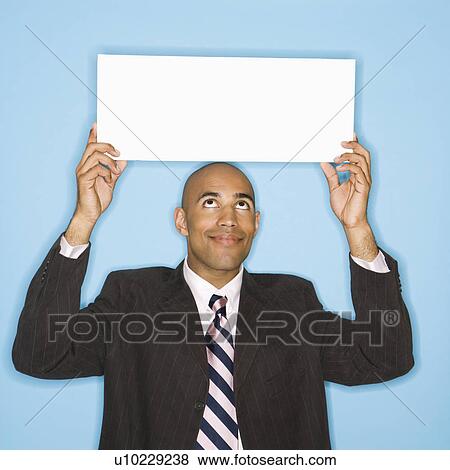 Man holding blank sign against blue background View Large Photo Image Stock Photo - Man holding blank sign against blue background. Fotosearch