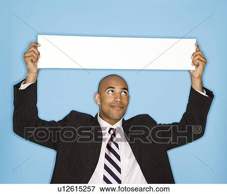 Stock Photo - Man holding blank sign against blue background. Fotosearch