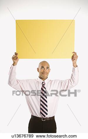 Man holding blank yellow sign overhead standing against white background View Large Photo Image Stock Photo - Man holding blank yellow sign overhead standing against white background. Fotosearch