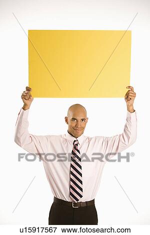 Stock Photo -  man holding blank yellow sign overhead standing against white background.. Fotosearch