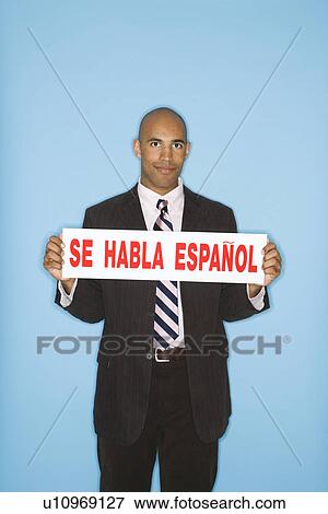 Man holding sign reading se habla espanol against blue background View Large Photo Image Stock Photo - Man holding sign reading se habla espanol against blue background. Fotosearch