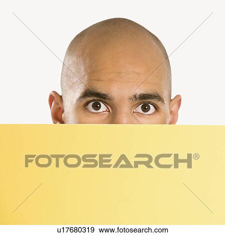 Stock Photo - Man peeking over blank yellow sign. Fotosearch