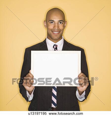 Man smiling holding blank sign against yellow background View Large Photo Image Stock Photography - Man smiling holding blank sign against yellow background. Fotosearch