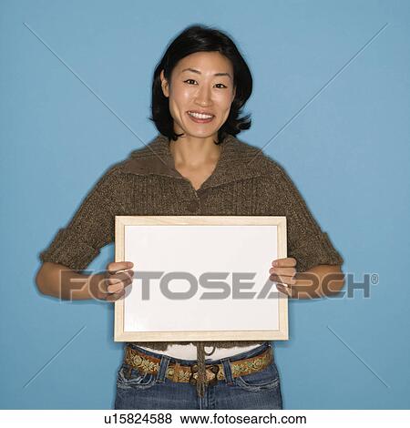 Woman holding blank sign on blue background View Large Photo Image Stock Photo - Woman holding blank sign on blue background. Fotosearch