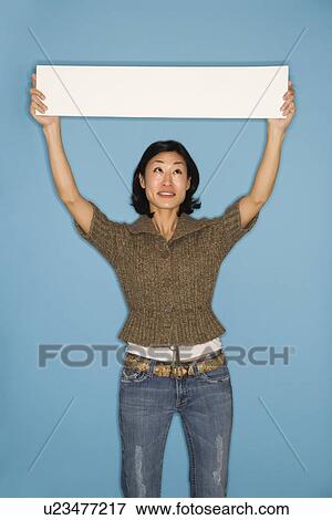 Stock Photo - Woman holding blank sign on blue background. Fotosearch