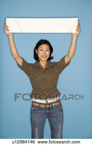 Woman holding blank sign on blue background View Large Photo Image Stock Photograph - Woman holding blank sign on blue background. Fotosearch