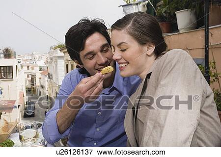Stock Photo - Man feeding woman at restaurant. Fotosearch