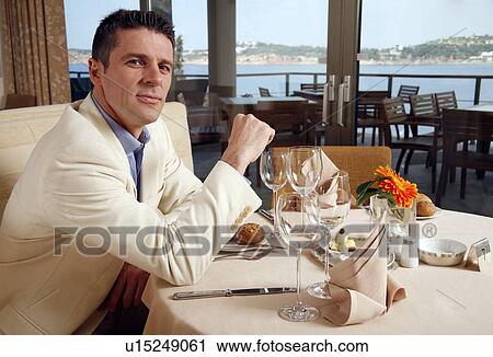Man sitting in at the table in a restaurant View Large Photo Image Stock Image - Man sitting in at the table in a restaurant. Fotosearch