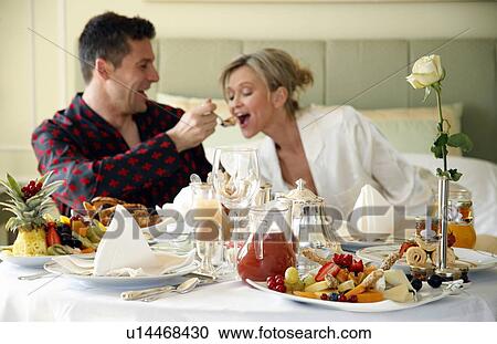 Stock Image - Mature couple having room service breakfast. Fotosearch