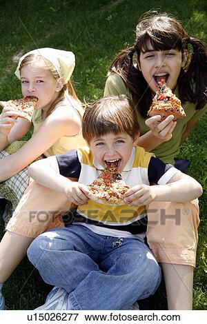 Three children eating pizza View Large Photo Image Stock Photo - Three children eating pizza. Fotosearch
