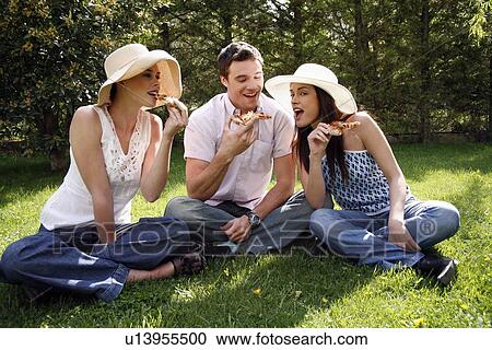 Stock Image - Three friends eating pizza. Fotosearch