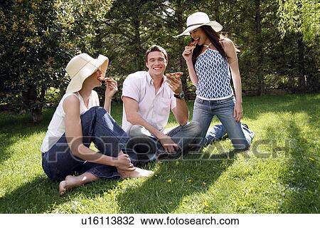 Stock Image - Three friends eating pizza. Fotosearch