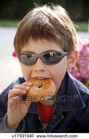 Young boy eating a doughnut View Large Photo Image Stock Image - Young boy eating a doughnut. Fotosearch