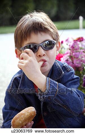 Young boy eating a doughnut View Large Photo Image Stock Photo - Young boy eating a doughnut. Fotosearch