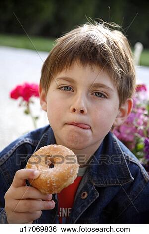 Stock Photograph - Young boy eating a doughnut. Fotosearch