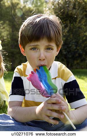 Young boy licking a lollipop View Large Photo Image Stock Photograph - Young boy licking a lollipop. Fotosearch