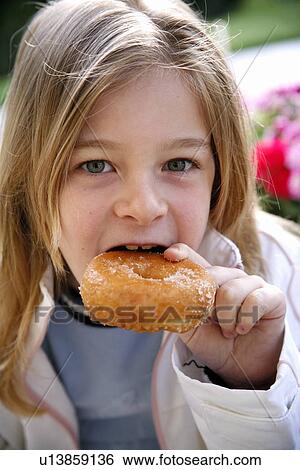 Young girl eating a doughnut View Large Photo Image Stock Photograph - Young girl eating a doughnut. Fotosearch