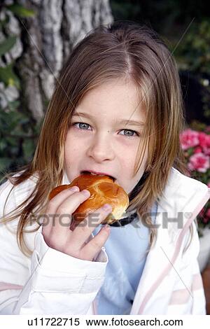 Young girl eating a doughnut View Large Photo Image Stock Photography - Young girl eating a doughnut. Fotosearch